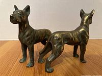 Two cast iron Great Dane dog figurines shown from different angles on wood floor and white background to display condition and size.