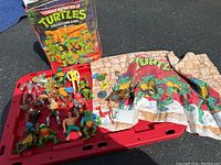 Overall lot showing vintage TMNT figures, accessories, red carrying case, pillowcase, and original collectors case box