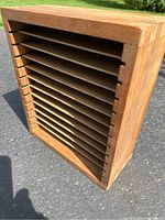 Front angled view of the wooden organizer box showing the slatted storage compartments inside.