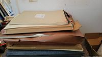 Stack of large sheets of art paper in brown kraft and cream colors, some stacked pads visible