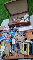 Overview of art supplies including brushes in a suitcase, pencils, chalk, scissors, pencil sharpeners and other miscellaneous items.