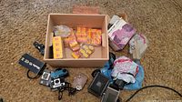 Overview of lot showing multiple cameras, film boxes, flash, viewer and carrying case on carpet