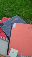 Photo of three stacked sketch/storyboard pads with visible covers: orange storyboard pad, gray 'ad art' pad, red sketch pad beneath.