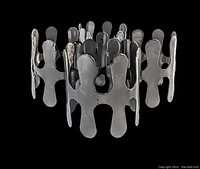 Four mid century metal napkin rings arranged in a circle, showing their abstract cutout shape and reflective surface with some tarnish.