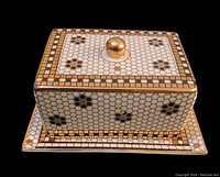 Covered butter dish with gold spherical handle, hexagonal mosaic tile pattern in white, black and gold on lid and base.