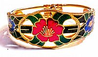 Front view of vintage cloisonne hinged bracelet showing vibrant cloisonne floral designs in red, green, blue, and black on gold-tone metal.