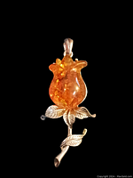 Front view of the vintage amber-colored rose pendant showing detailed amber flower and silver-toned leaves.