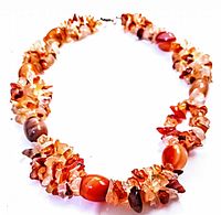 Photo showing the raw agate chip beads with larger polished agate oval beads on a warm-tone necklace with metal clasp.