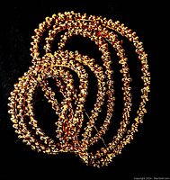 Top-down image showing the gold-toned vintage Scassi brooch with multiple looped textured sections coiled on a black background.