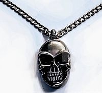 Close-up of the silver-tone skull pendant showing detailed facial features and bail for chain attachment.
