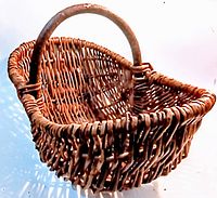 Side angle view of the vintage wicker basket showing the handwoven wicker pattern and single handle.
