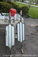 Two decorative metal fleur de lis mirrors with distressed white panels and black metal frames, outdoor setting
