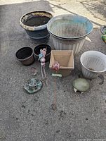 Overview of garden planters of various sizes and materials, and metal art items on pavement