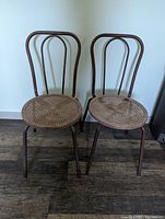 Front view of two bentwood style metal chairs with woven plastic seats