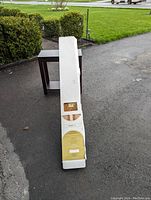 Photo showing two boxed blinds stacked, long white rectangular box, taken outdoors.