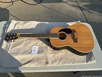 Full view of the Spectrum AIL36NL acoustic guitar on a white cloth showing natural wood finish and dreadnought shape.
