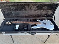 Full view of the silver Ibanez Soundgear bass guitar in open black hard case with plush interior.