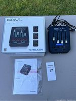 Full lot contents including TC Helicon GOXLR Mini mixer, original box, quick start guide, and MaxSold tag on table outside.