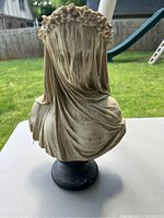 Front view of veiled woman bust sculpture showing detailed floral crown and folds of veil draping her face and shoulders.