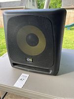 Front view of KRK 10s subwoofer with black metal grille and visible yellow speaker cone.