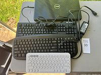 Dell laptop closed with black wired keyboard and power adapter on top.