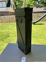 Side view of large green military metal ammo can with stencil text, indicating 7.62mm cartridges capacity and weight 9.4 lbs.