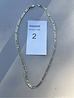 Full view of the flat curb link chain necklace laid around a MaxSold card labeled ‘2’.