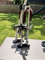Pair of aluminum stilts with footrests, springs, and straps, photographed outside on a table with grass background.