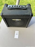 Front view of the small black Kustom amplifier with textured covering and metal grille showing the Kustom logo.