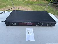 Front view of Pyle PDWM2450 wireless microphone system receiver with visible antennas, power switch, LCD display, and control knobs placed on a table outdoors.