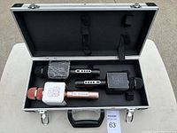 Three wireless microphones inside black padded carrying case, two black and one rose gold, with Pop Solo logo on plastic collar.