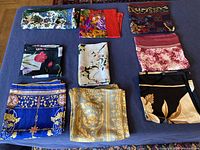 Overview photo showing all nine folded vintage silk scarves in various floral and ornamental patterns.