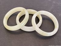 Top view of three agate stone bangles overlapping on a dark surface.