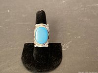 Front view of the ring showing the large oval turquoise stone set in a silver bezel with engraved designs.