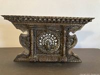 Front view of the carved wood window showing central peacock design and overall shape.