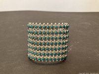 Front view of cuff bracelet showing eight rows of round turquoise stones in bezel settings on sterling silver cuff