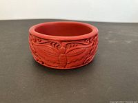 Front view showing butterfly carving on cinnabar bangle