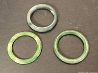Top-down view of the 3 jade bangles arranged in a triangle on a dark surface.