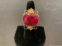 Front view of the ring showing large faceted ruby set on gold gilt silver with decorative metal work.