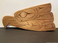 Front view of full cedar carving showing stylized bird form and carved motifs