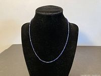 Full front view of the sapphire necklace on a black display bust showing overall length and bead arrangement.