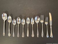 Row of 11 pieces: 8 spoons, 2 forks, 1 knife laid flat