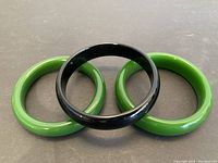 Three bangles arranged with green bangles on the sides and black bangle in center, showing glossy smooth finish.
