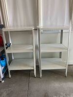 Front view of two metal utility shelves side by side in a room against a white wall.