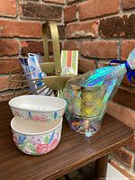 Photo showing the ceramic floral soap dish and bowl, gold metal basket, Oral B toothbrush heads, guest soaps in box, and the Bath and Body Works pedestal candle wrapped in iridescent plastic.