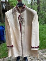 Beige men's Indian formal garment with hand-stitched beadwork on the collar, chest, and cuffs, hanging outside showing front and sleeves.