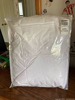 Photo showing white queen size down comforter in original clear plastic packaging with label from Sears Canada indicating size and usage.