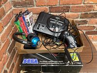 Overall lot showing Sega Genesis console in original box, controller, headphones, power adapter, and game cartridges.