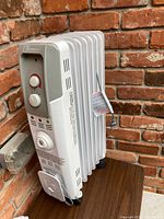 Side and angled view of the white Garrison oil-filled radiator space heater showing fins and power cord wrapping hook.