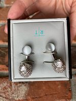 Pair of silver-tone metal hedgehog cufflinks with small grey spheres held in grey and black box labeled 'R T'